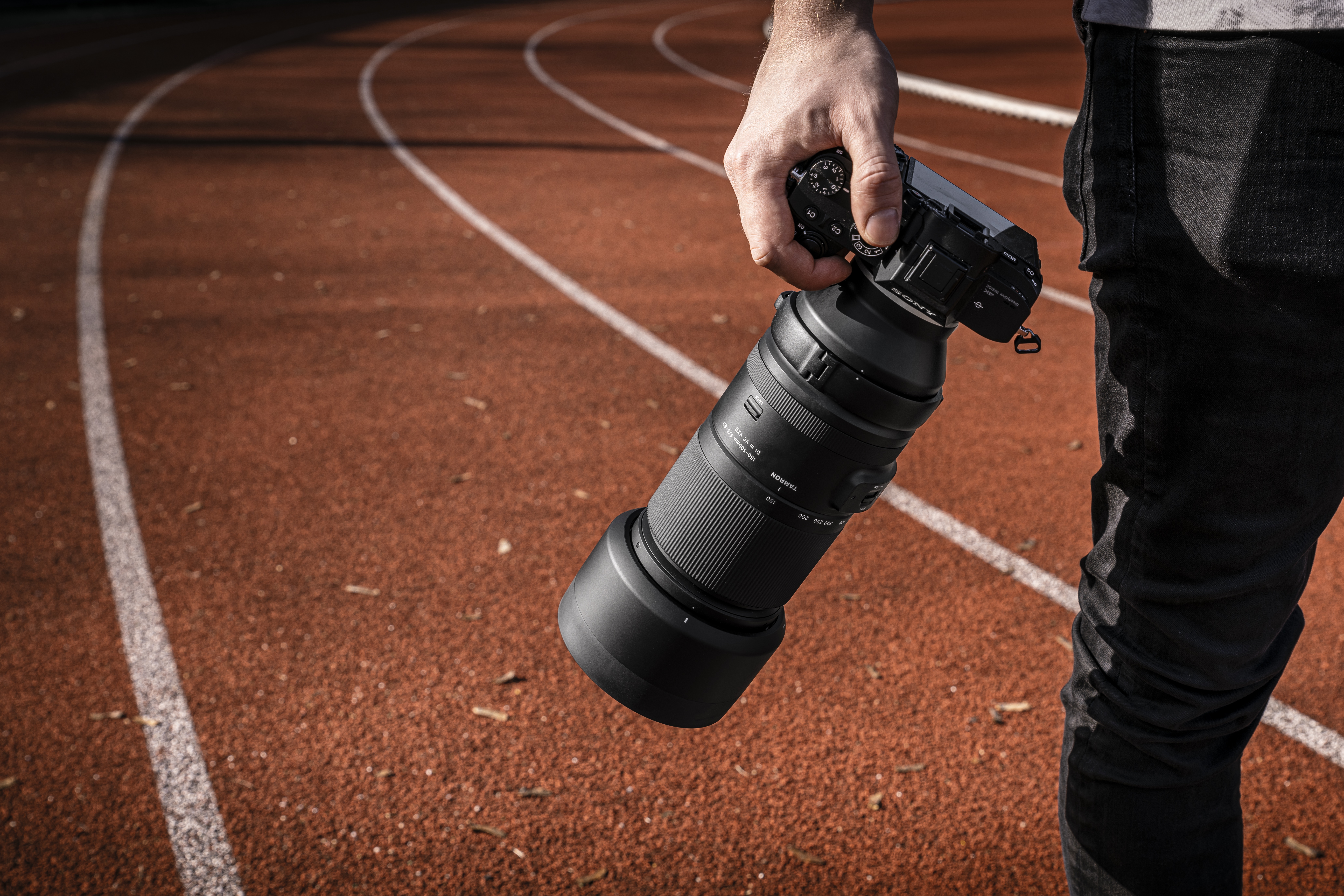 Tamron objektiv na Sonyjevom fotoaparatu u ruci fotografa na atletskoj stazi